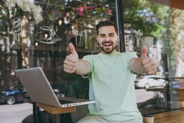 Smiling freelancer friendly happy student young man in casual mint t-shirt work online with laptop...