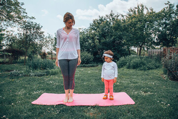 Woman doing yoga with her little girl. Healthy lifestyle.