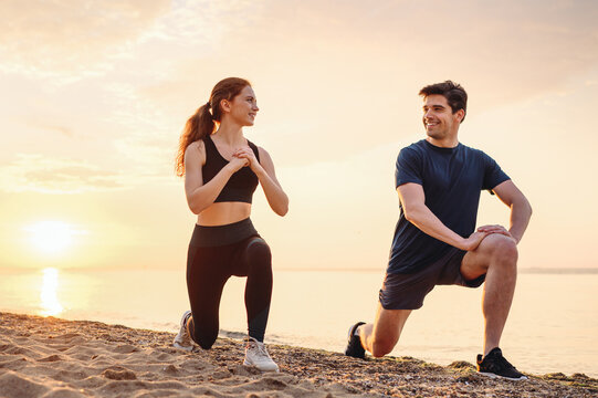 Full body couple young two friend strong sporty sportswoman sportsman woman man in sport clothes warm up training do lunges do exercise on sand sea ocean beach outside on seaside in summer day morning