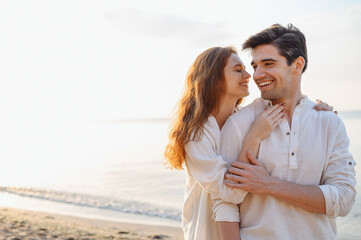 Obraz premium Romantic young couple two friends family man woman 20s in casual clothes hug girlfriend going to kiss boyfriend at sunrise over sea sand beach ocean outside exotic seaside in summer day sunset evening