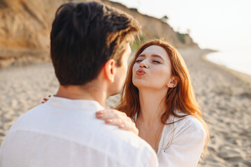 Happy lovely young couple two friends family man woman in white clothes girlfriend going to kiss boyfriend enjoy together at sunrise over sea beach ocean outdoor seaside in summer day sunset evening.