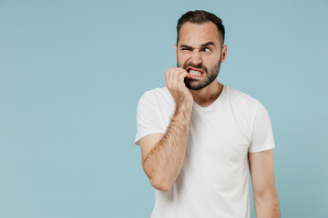 Young confused embarrassed sad puzzled man 20s wearing casual white t-shirt looking aside biting...