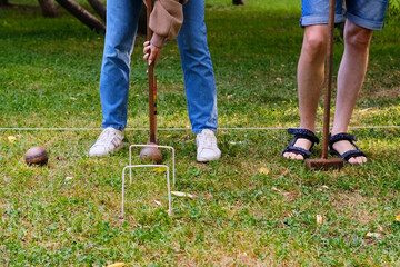 Person plays a sports game of croquet on a green field strike mallets on a ball and conducts...