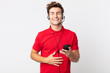 young handsome man laughing out loud at some hilarious joke with a smartphone and headset