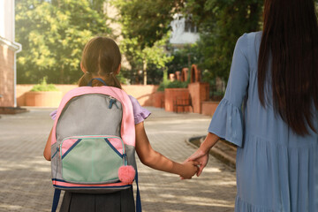 Mother taking her daughter to school, back view