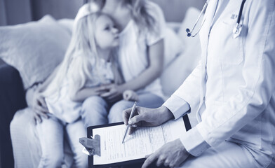 Doctor and patient. Pediatrician using clipboard while examining little girl with her mother at home. Sick and unhappy child at medical exam. Medicine concept
