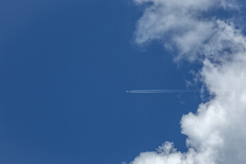 青空を背に積雲を切り裂いた飛んできた飛行機