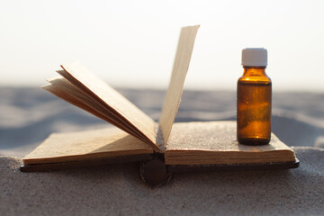 Open old book with seashells on the sand. Bottle on sand, Copy space for text.