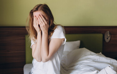 Close up young blonde woman feeling upset, sad, disappoint crying lonely in green bedroom. Emotional shock and life problems, domestic violence
