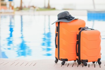 Travel, summer holidays and vacation concept. pink suitcase with hat on background of hotel pool area in Egypt.