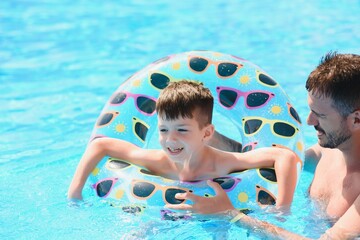 Father teaching his little son to swim in swimming pool. Vacation concept.