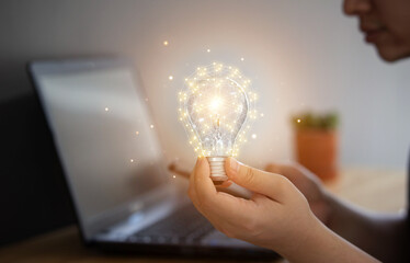 Knowledge development and inspiration concept. Hand of a businessman holding illuminated light bulb, businessman show new ideas with innovation and creativity.