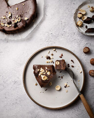 A piece of chocolate cake with nuts on a plate. Chocolate dessert on a fork on a light background. Brownies with hazelnuts and dark chocolate