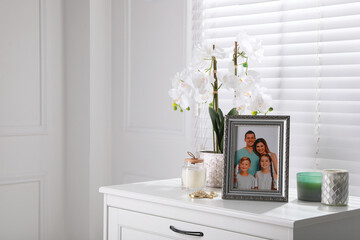 Framed family photo and orchid flower on drawer indoors, space for text