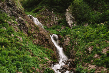 Fototapeta na wymiar Beautiful mountain waterfall among trees, summer natural background