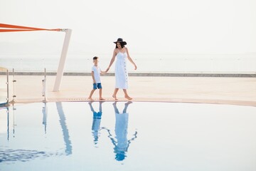 Fototapeta na wymiar Cute happy family having fun near pool on luxury tropical resort, mother with child, summer holidays, love concept