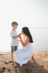 Mother and son playing on the beach at the day time. Concept of friendly family.