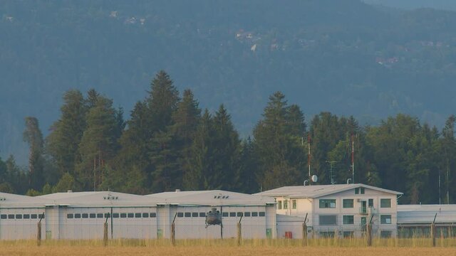 Slovenian army helicopter landing in Ljubljana international airport. Slow motion view of chopper descending. Alps mountains in the background