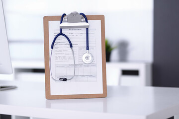 Stethoscope and clipboard with medication history records are on the table at the doctor's working place. Medicine and health care concept