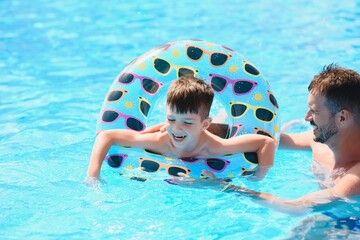 Father teaching his little son to swim in swimming pool. Vacation concept.