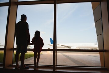 Fototapeta premium Exhausted father and daughter staying at the airport for a long time. Their flight was canceled. Copy space in right side