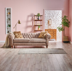 Grey and brown classic sofa with blanket and pillow in front of the white brick and pink wall background, gold lamp, frame and bookshelf, wooden cabinet style, home interior concept.