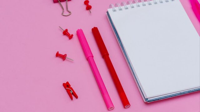 Stationery in pastel pink shades. On a pink background, flat lay. Markers and pencils with pens, spiral notebook top view. Copy space. High quality 4k footage