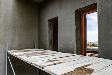 Applying fresh construction glue layer on insulated wall for covering fiberglass reinforcing mesh on mineral wool.