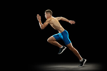 Leader, champion. Young professional male athlete, runner training isolated on dark studio background. Muscular, sportive man. Concept of sport, healthy lifestyle