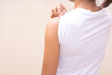 Woman white shirt showing her arm after receiving vaccine shot on White background.