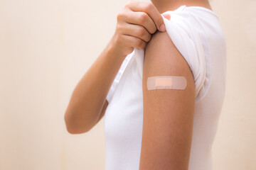 Woman white shirt showing her arm after receiving vaccine shot on White background.