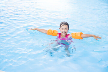 Pretty little girl swimming in outdoor pool and have a fun