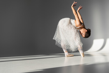 Side view of ballerina bending on grey background © LIGHTFIELD STUDIOS