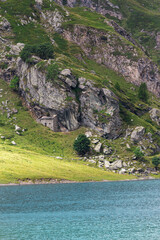 Mountain house in the middle of the alps. Summer in the green mountain with a little house. Alpine mountains with a play of light and shadow of the clouds.