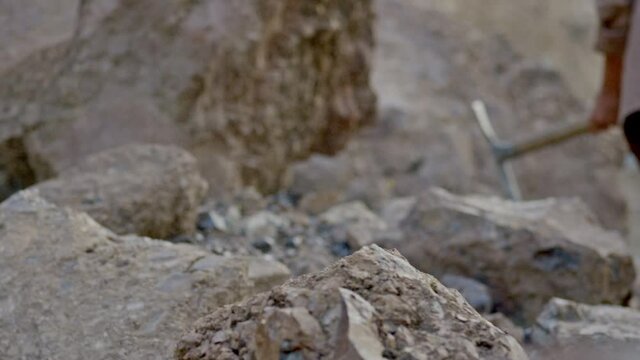 Miner or gold digger breaking rock by digging axe . Close up of pickaxe hitting rocks .  Shot on RED EPIC DRAGON Cinema Camera in slow motion.