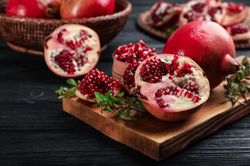 Delicious ripe pomegranates on black wooden table