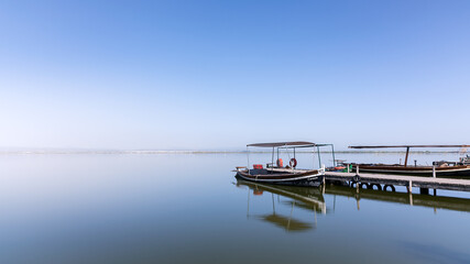 Barcas sobre agua como espejo en laguna de la albufera de Valencia. Azul. Tranquilidad. Paz