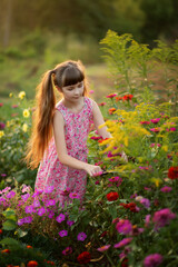 Photo of a beautiful girl with long hair in pink flowers at sunset.