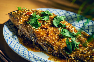 Whole fried carp with hot sauce and Sichuan pepper. Wood background. Chinese cuisine