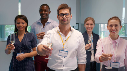 Multiethnic team looking at camera and raising glass wit champagne