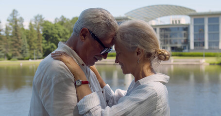 Side view portrait of senior couple hugging outdoors near lake