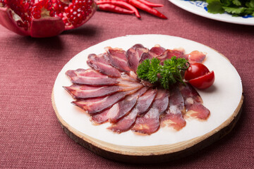 Sliced raw smoked meat served on wooden board