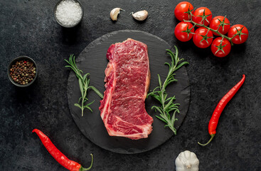 Raw marbled beef New York steak with spices on a stone background