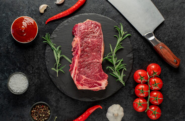 Raw marbled beef New York steak with spices on a stone background