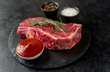 Raw marbled beef New York steak with spices on a stone background