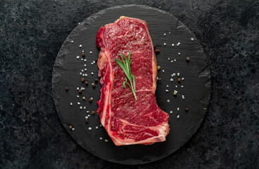 Raw marbled beef New York steak with spices on a stone background