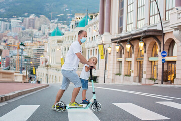 Father and child,  riding scooter in Monaco village on sunset