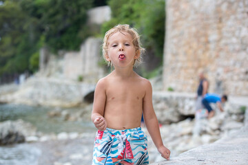 Cute child, blond toddler boy, holding sea urchin on the beach