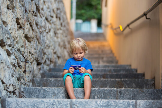 Happy beautiful children, playing on stone stairs in old town, taking pictures