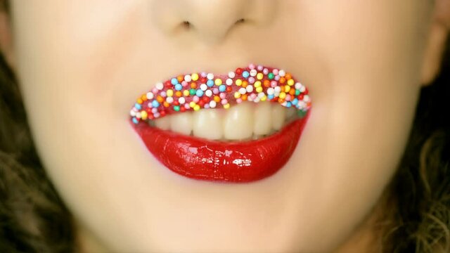 Closeup of a beautiful woman lips with beautiful colorful make up and candy balls sending air kiss . Close up of girl's mouth having flirty emotions and sending air kiss .	

